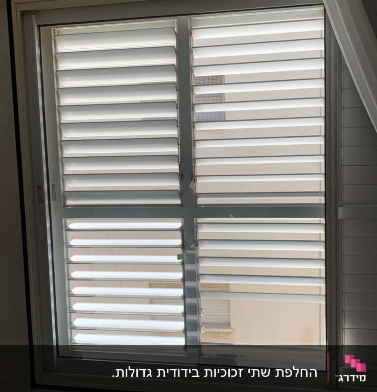 חלון עם תריסים סגורים ומסגרת זכוכית.
